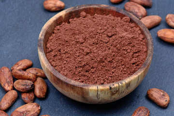 Bowl with cacao powder and beans on slate