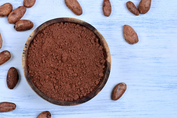 Bowl with cacao powder and beans on table