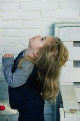 Child with long blond hair in blue pajama looking up