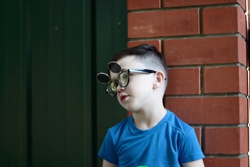 The Image of a little boy beautiful brunette in glasses standing outdoors on a metal door, a conversation with a friend to go walking. Attractive guy, having a conversation