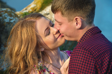 Young happy couple kissing on nature against the beautiful Caucasian landscape.