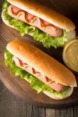 Tasty barbecue grilled hot dog with salad,yellow mustard, onion, ketchup, and French fries on wooden background. Junk and fast food concept.