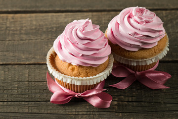 Closeup of cupcakes with vanilla, berries, pink and white cream, chocolate and sprinkles on wooden background. Selective focus. Sweet dessert tasty food concept muffin.
