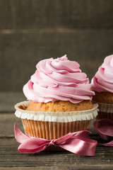 Closeup of cupcakes with vanilla, berries, pink and white cream, chocolate and sprinkles on wooden background. Selective focus. Sweet dessert tasty food concept muffin.