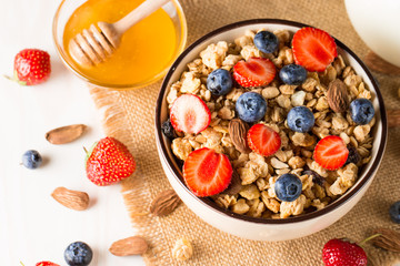 Healthy breakfast concept with oat flakes and fresh berries on rustic background. Food made of granola, muesli. Healthy banana smoothie with blackberries, muslie, strawberries, blueberries and honey.
