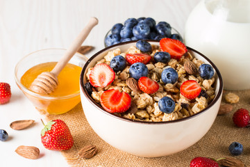 Healthy breakfast concept with oat flakes and fresh berries on rustic background. Food made of granola, muesli. Healthy banana smoothie with blackberries, muslie, strawberries, blueberries and honey.