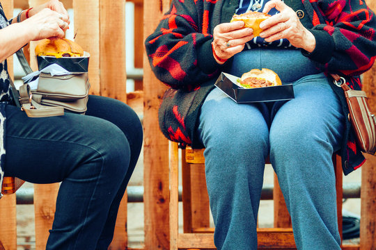 Two Older Women Eating Burgers On The Street