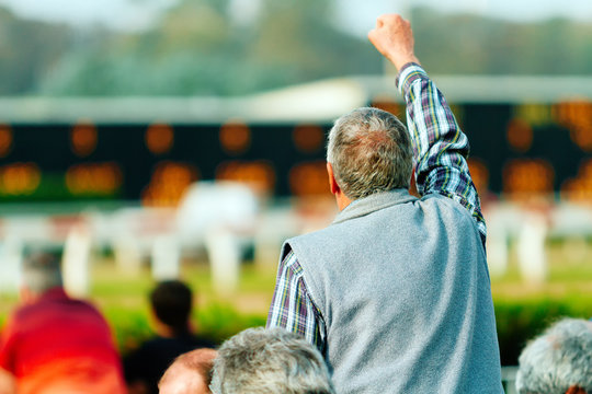 Gambler celebrates with his hand up on a racetrack