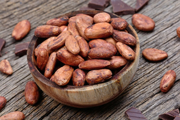 Bowl with cacao beans and dark chocolate on table