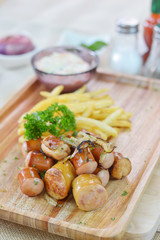 Obraz na płótnie Canvas Fried sausages and blur French fries with cream sauce on the wooden board