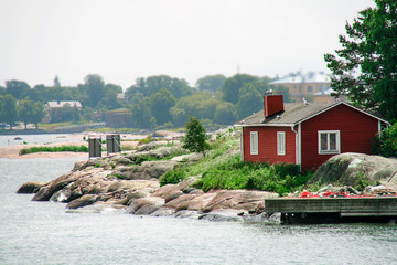 A small idyllic red cabin on a small islet the coast near Helsinki, Finland