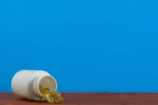 Bottle For Pills On A Red Wood Table. Beautiful Blue Background. 