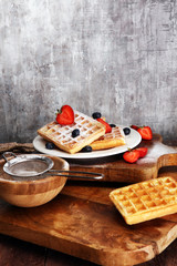 Homemade waffles with berries in plate on wooden table