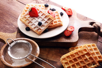 Homemade waffles with berries in plate on wooden table
