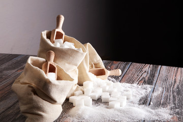 burlap with white sand and lump sugar on grey wooden background