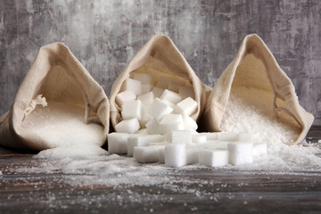 burlap with white sand and lump sugar on grey wooden background