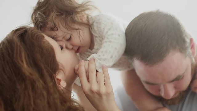 Mother kiss her doughter while she sits on the fathers neck