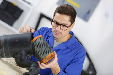 professional mechanic cleaning filter in his workshop