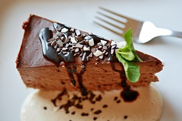 Chocolate cheesecake with mint on white plate with fork 