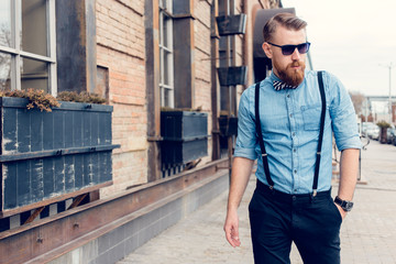 young guy with a beard and mustache with glasses posing on the street in the sunlight, fashion man, style, vintage style, retro men, handsome beard, outdoor portrait, hipster man