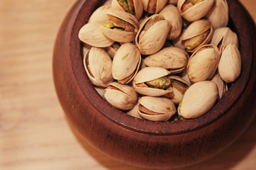 Pistachio nuts in little wooden bowl isolated