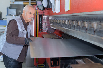 man controlling hydraulic press machine for cutting steel - obrazy, fototapety, plakaty