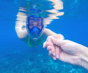 Fototapeten Snorkeling woman in full-face snorkeling mask. Swimming girl holds hand of partner © Elya.Q