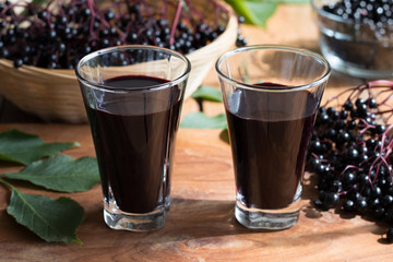 Two glasses of elderberry syrup on a wooden background