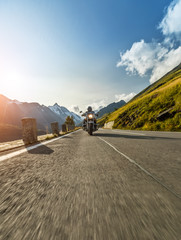 Fototapeta premium Kierowca motocykla jedzie na autostradzie alpejskiej. Fotografia plenerowa