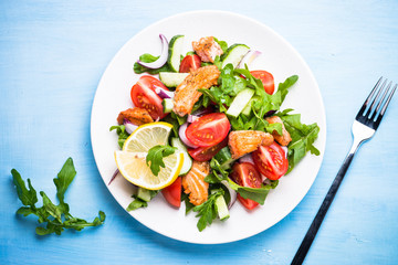 Fresh salad with salmon and vegetables. Top view on blue table.