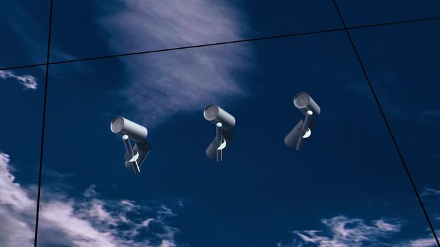 cctv working on glass office building with reflection of sky and clouds