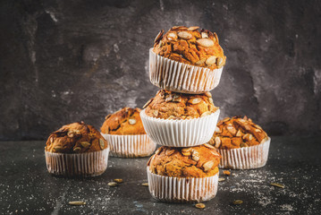 Autumn and winter baked pastries. Healthy pumpkin muffins with traditional fall spices, pumpkin seeds. Black stone table, copy space