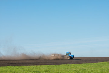 blue tractor plowing the field
