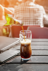 A large glass of dark beer on a pub background on a wooden table. Tinted Windows.