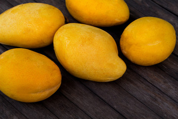 Yellow mango on wooden background. Bunch of tropical fruits.