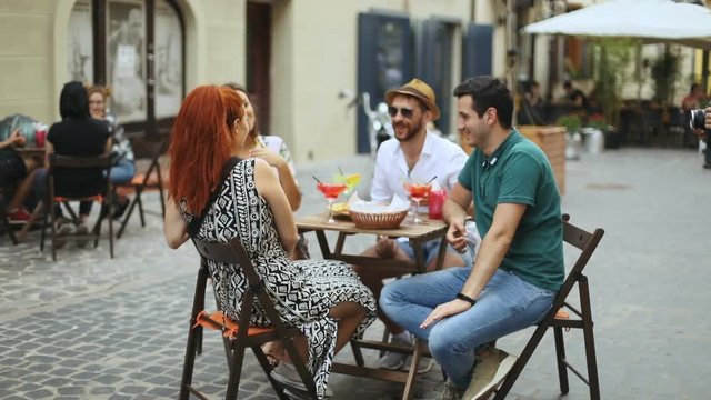 Friends concept - group of young friends spending time in street cafe, drinking cocktails chill relax entertainment chit chat talking conversation relax chill friendship emotions positive youth