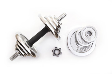 Top view of an adjustable metal dumbbell with a set of extra plates on white background.