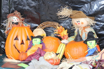 Decorative display of small pumpkins, Halloween objects, squash, and corn.

