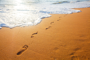 Fototapeta na wymiar beach, wave and footprints at sunset time