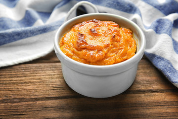 Ramekin with tasty carrot souffle on wooden table