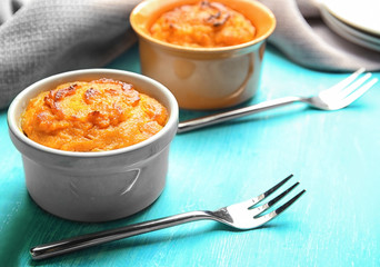 Ramekins with tasty carrot souffle on wooden table