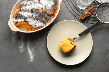 Spoon and baking dish with tasty carrot souffle on table