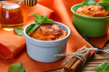 Ramekins with tasty carrot souffle on wooden table