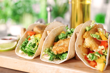 Wooden holder with yummy fish tacos on kitchen table