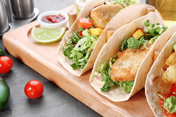 Wooden holder with yummy fish tacos on kitchen table
