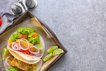 Wooden tray with delicious fish tacos on kitchen table