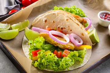 Wooden tray with delicious fish tacos on kitchen table