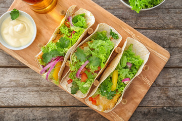 Wooden holder with yummy fish tacos on kitchen table