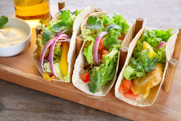 Wooden holder with yummy fish tacos on kitchen table