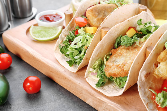 Wooden holder with yummy fish tacos on kitchen table